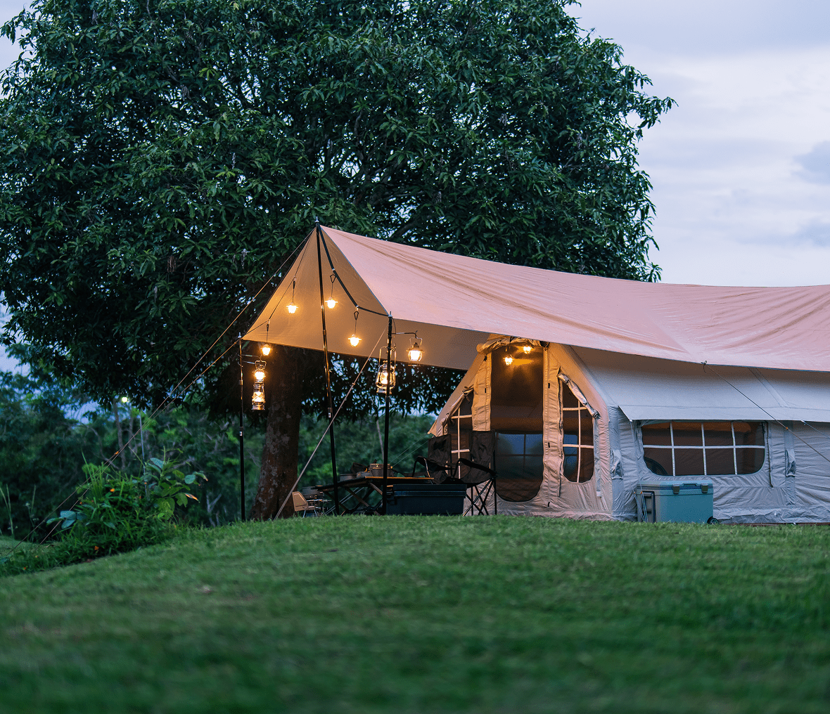 Glamping tent with lights in natural setting.