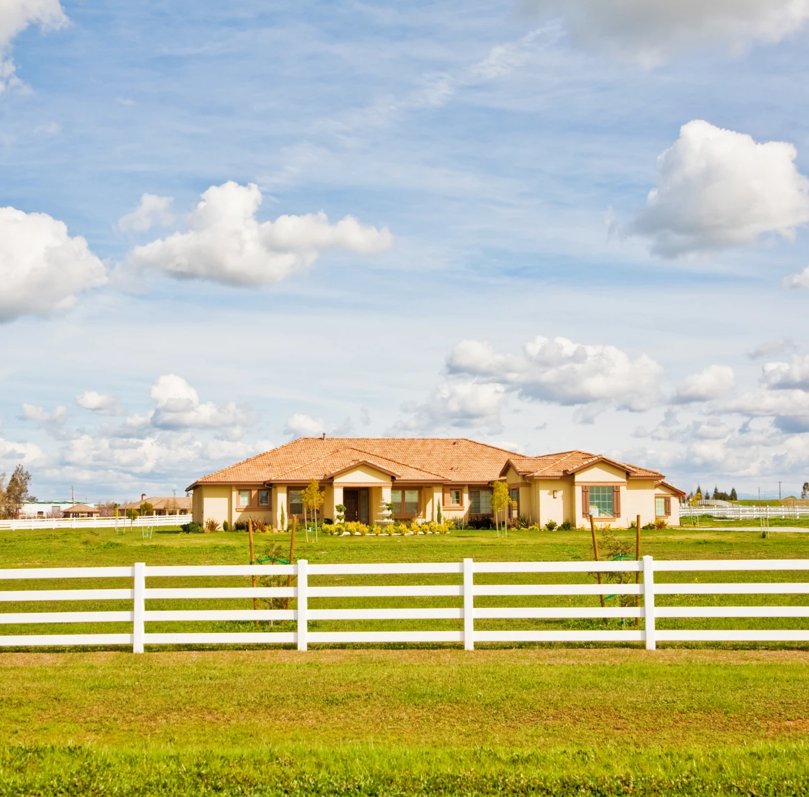 House with white fence under cloudy sky.